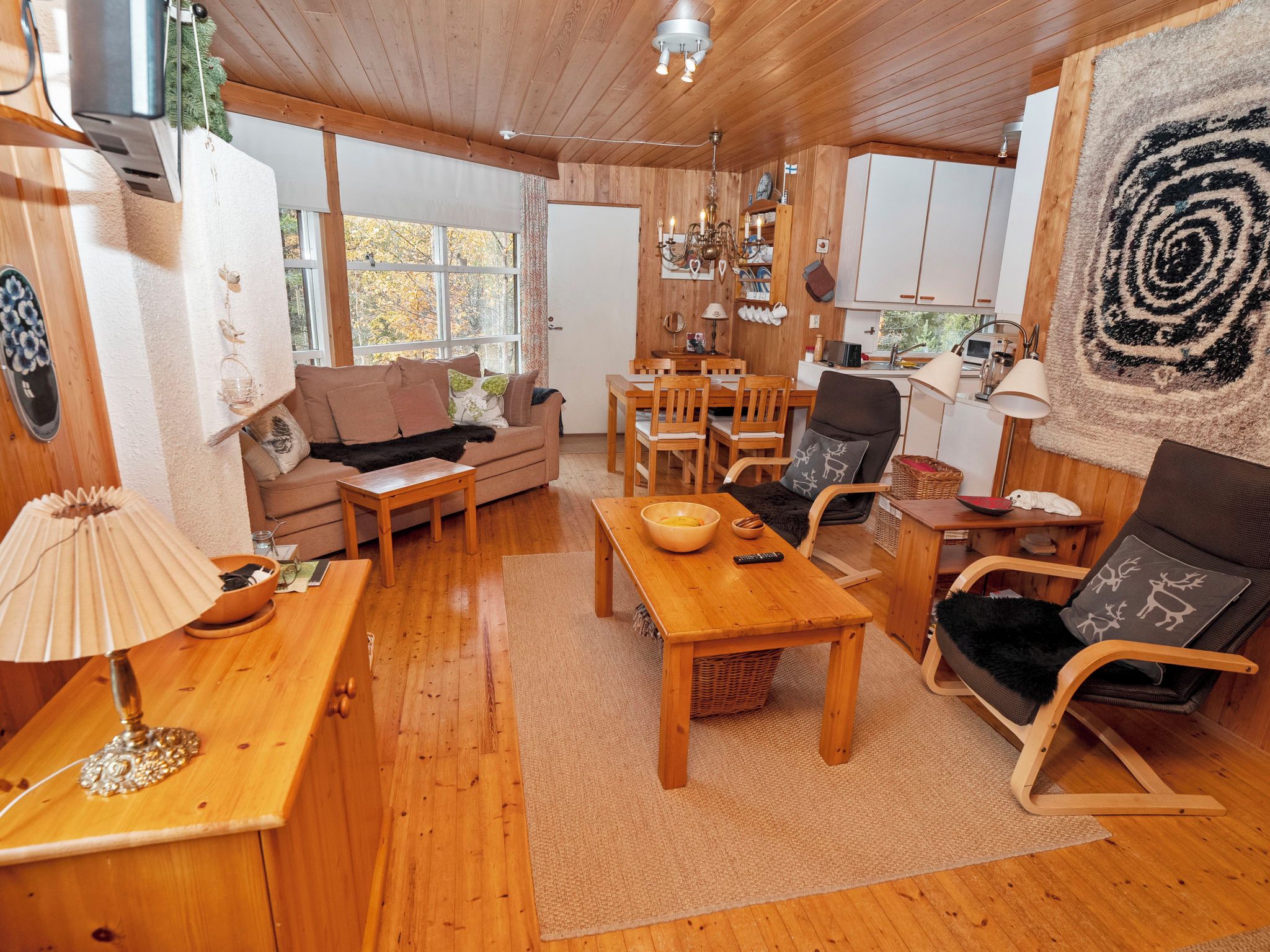 Een gezellig chaletinterieur met een houten vloer, een bank, een eettafel en een stoel.