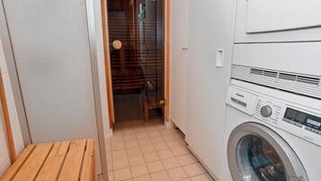 Une buanderie équipée d’un lave-linge, d’un banc en bois et d’une porte donnant sur une autre pièce.