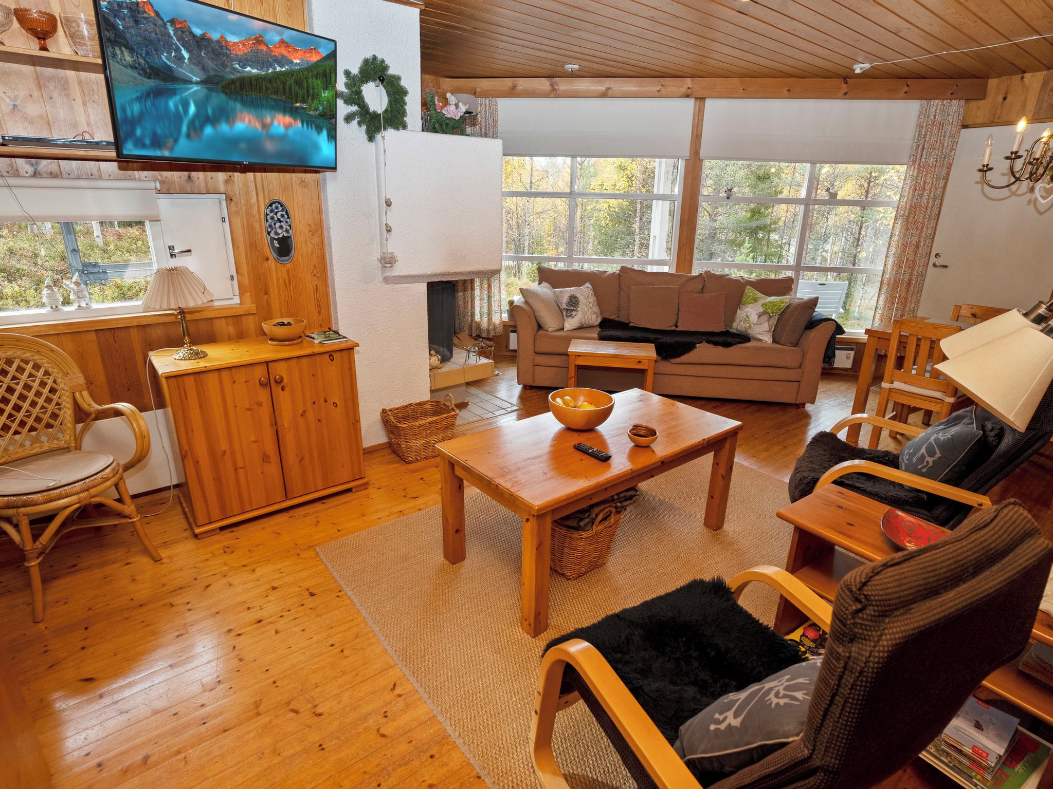 A cozy living room with a wooden floor, a sofa, a coffee table, and a television mounted on the wall.