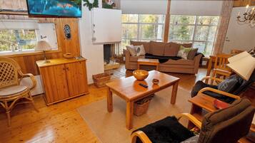 Un salon chaleureux avec un plancher en bois, un canapé, une table basse et un téléviseur fixé au mur.
