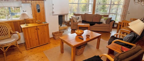 A cozy living room with a wooden floor, a sofa, a coffee table, and a television mounted on the wall.