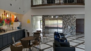 Eine moderne Hotelhalle mit Küchenzeile, Sitzgelegenheiten und Blick auf den Aufzug.