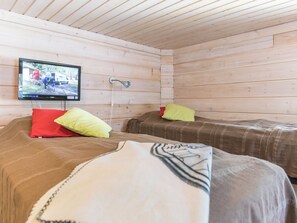 A cabin room with two beds, a television mounted on the wall, and a wooden ceiling. - Poropahta b by Interhome (Kuusamo)