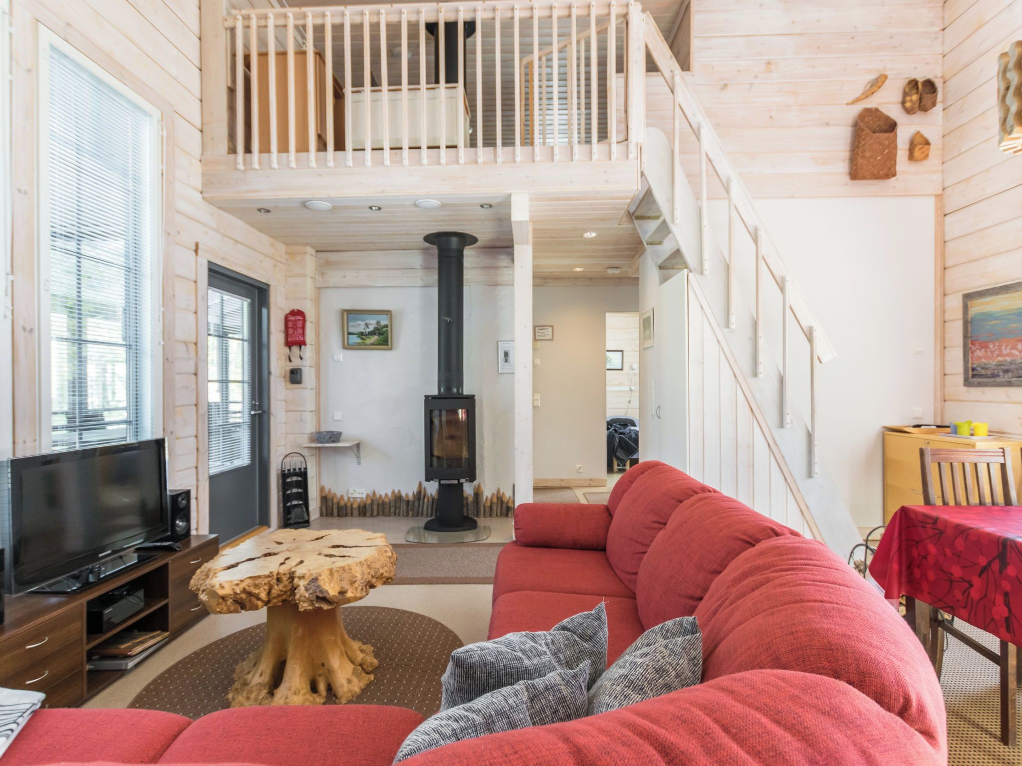 Un salon spacieux avec un canapé rouge, une table basse en bois, un téléviseur et une cheminée.