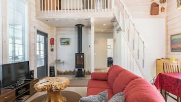 Un salon spacieux avec un canapé rouge, une table basse en bois, un téléviseur et une cheminée.