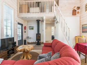 A spacious living room with a red sofa, a wooden coffee table, a television, and a fireplace. - Poropahta b by Interhome (Kuusamo)