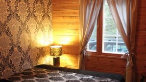 Habitación de cabaña de madera con cama, lámpara y ventana con cortinas.
