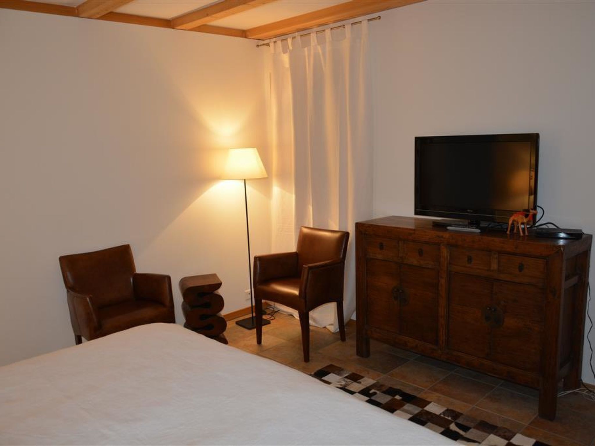 Ein Hotelzimmer mit einem Bett, einem hölzernen Schminktisch, einem Fernseher und zwei Stühlen.