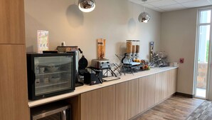 Un coin cuisine équipé d’un four à micro-ondes, d’une machine à café et d’un présentoir pour les aliments.