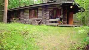 Eine Blockhütte mit Veranda, einem Fenster und einer Tür.