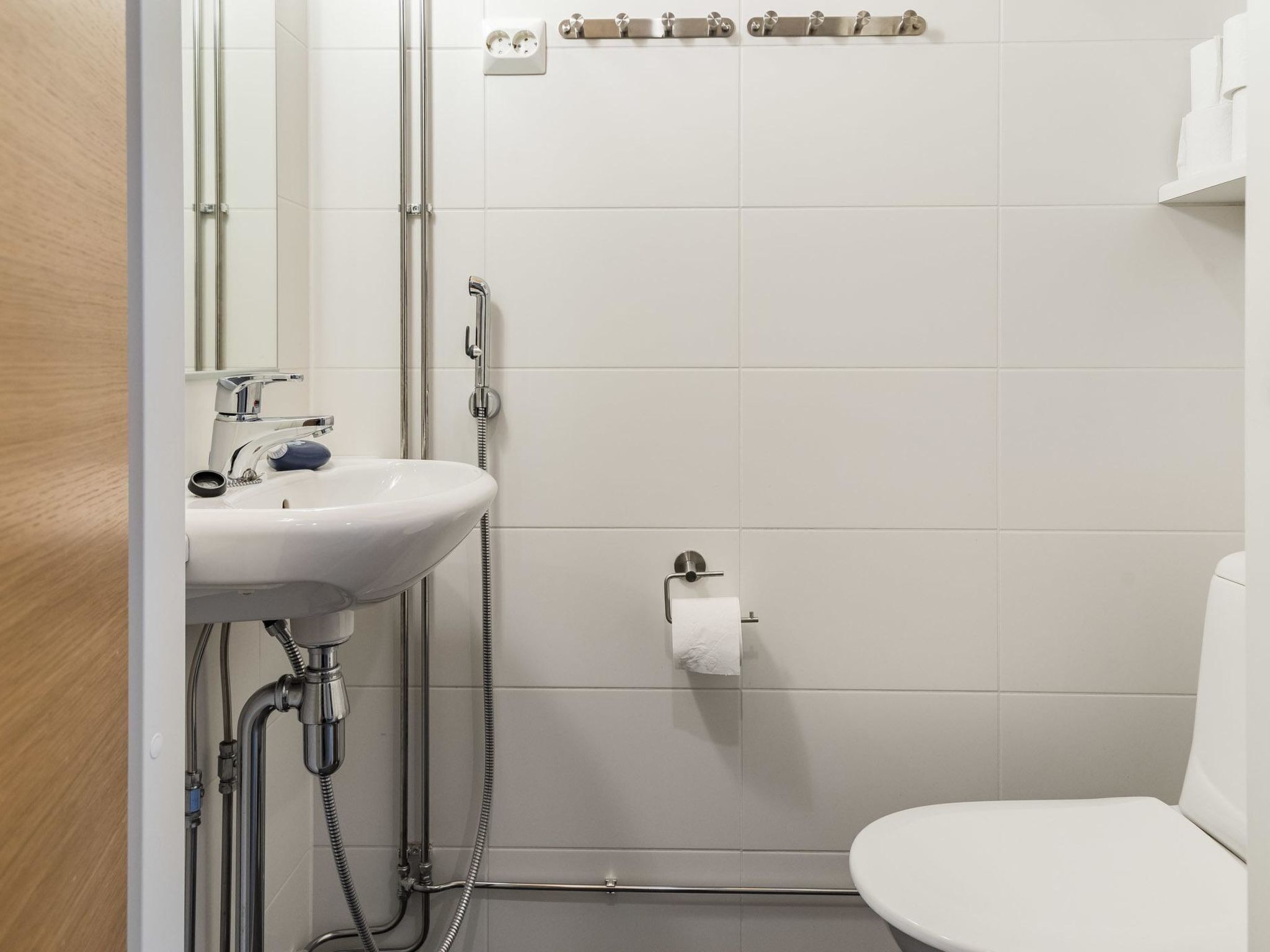Kylpyhuone, jossa on valkoinen pesuallas, wc ja suihkukaappi.