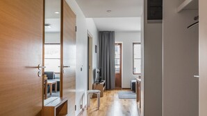A modern hotel room with a wooden door, a small seating area with a table and chairs, a desk with a chair, and a window with curtains. - Nordic chalet 9408 by Interhome (Ylläsjärvi)