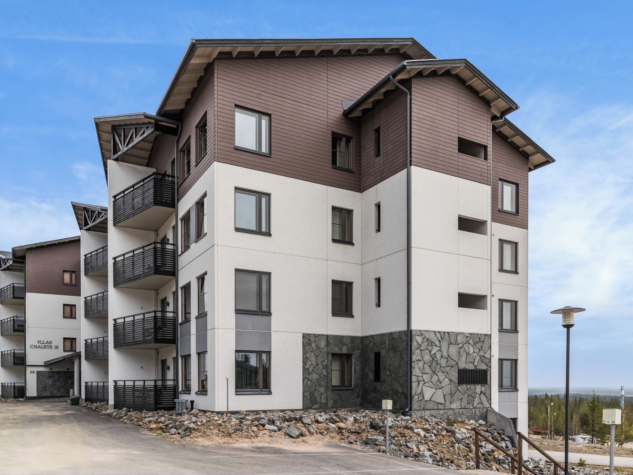 A multi-story residential building with balconies, a stone facade, and a clear sky.