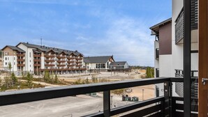 A view from a balcony overlooking a residential area with multi-story buildings, a parking lot, and a clear sky. - Nordic chalet 9408 by Interhome (Ylläsjärvi)