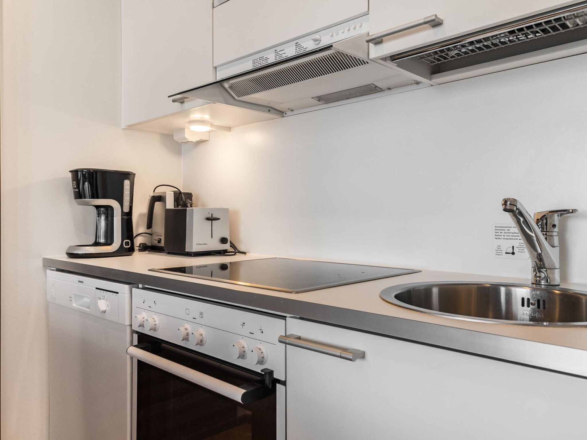 A modern kitchen with a built-in oven, a coffee maker, and a sink.