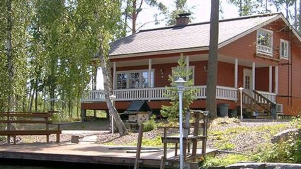 A wooden cabin with a porch, a dock extending into a body of water, and a picnic table nearby. - Pernoo 2 by Interhome (Kotka)