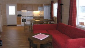 A compact living space with a kitchenette, a red sofa, and a dining table. - Pernoo 2 by Interhome (Kotka)