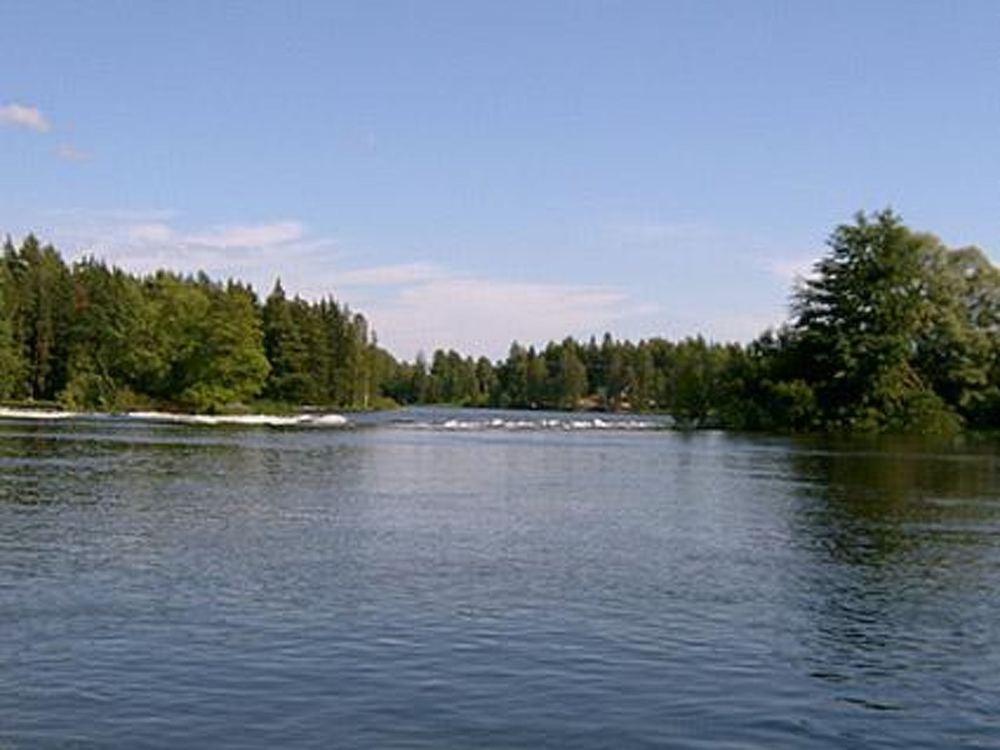 Une rivière paisible, bordée de forêts denses de chaque côté.