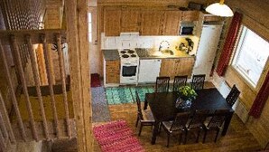 A rustic kitchen with wooden cabinets, a dining table with chairs, and a red rug. - Pernoo 2 by Interhome (Kotka)