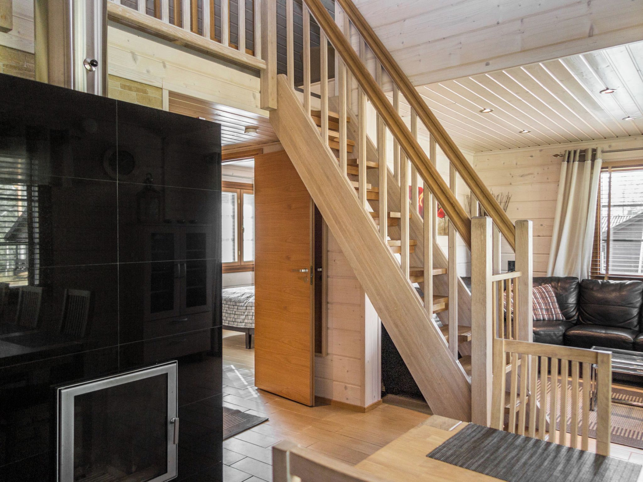 Een modern interieur met een houten trap, een zwarte entertainmentsunit en een leren bank.