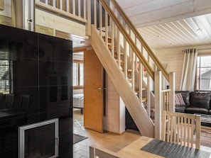 A modern interior with a wooden staircase, a black entertainment unit, and a leather sofa.