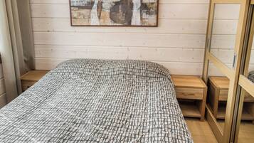 A bedroom with a bed, a wooden headboard, a nightstand, and a wall-mounted artwork.