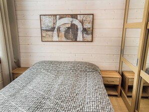 A bedroom with a bed, a wooden headboard, a nightstand, and a wall-mounted artwork.