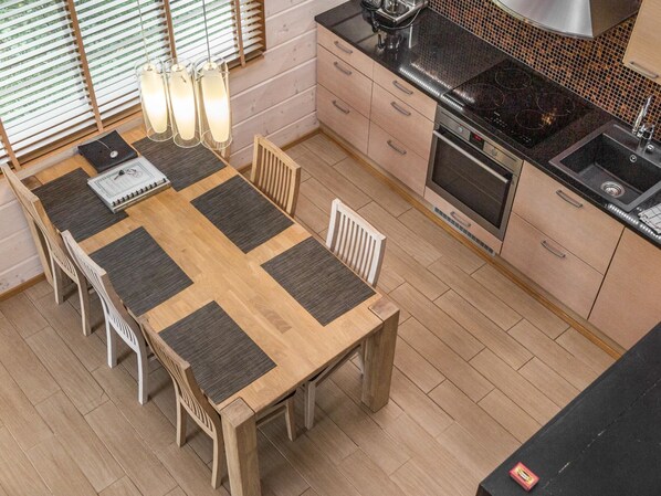 A modern kitchen with a wooden dining table, chairs, and a built-in stove.
