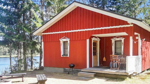 A red cabin with a porch, a grill, and a bench by a lake. - Vacation home Rajala by Interhome (Kaavi)