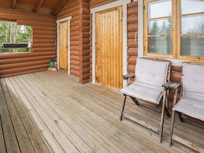 A log cabin with a wooden deck, two doors, and two white chairs. - Mäntymäki by Interhome (Raasepori)