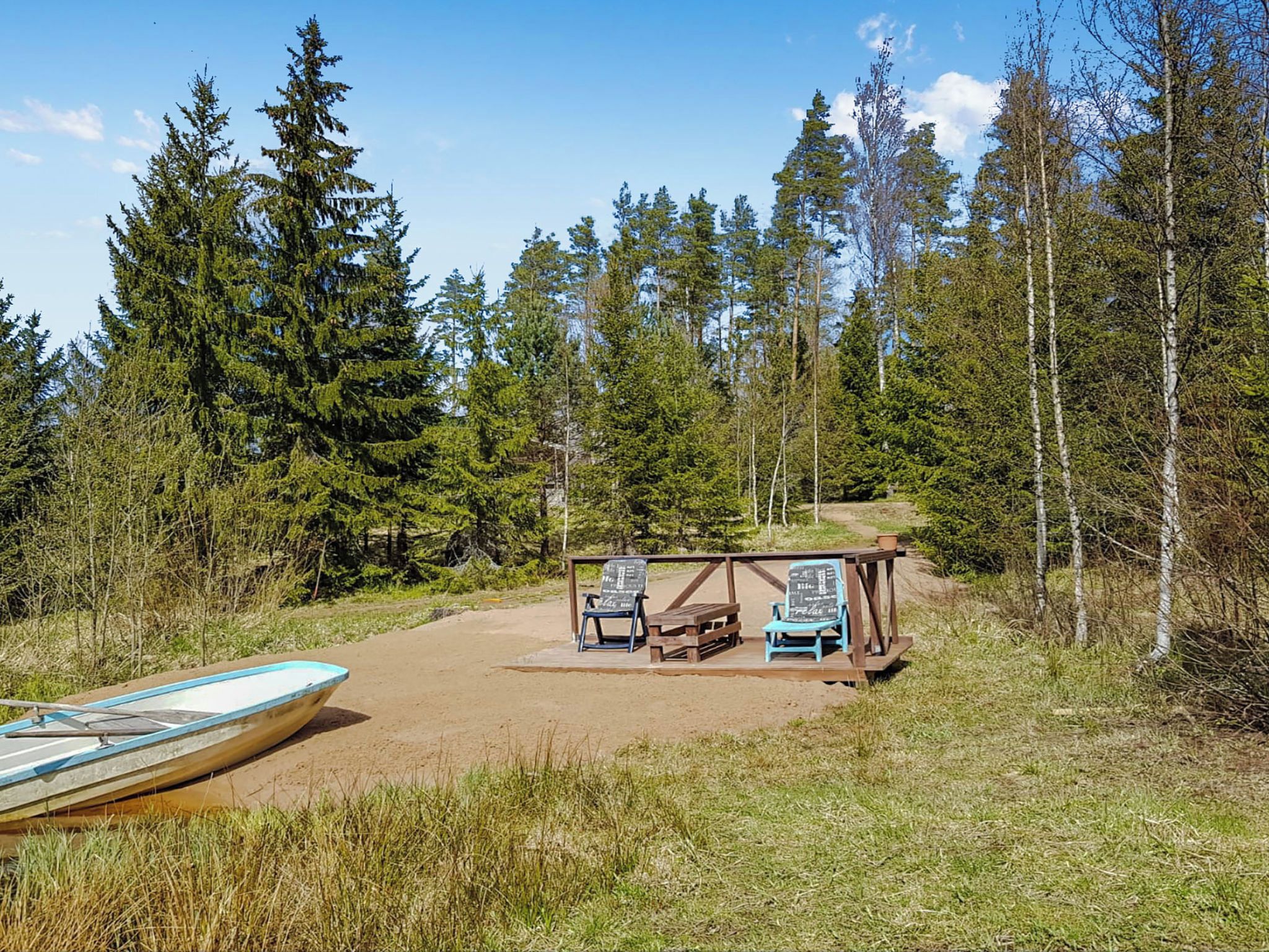 A campsite with a wooden shelter, two chairs, a bench, and a boat.