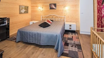A room with a bed, bedside tables, a television, and a refrigerator.