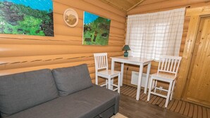 A cozy room with a grey sofa, a small white table with chairs, and two paintings on the wall. - Mäntymäki by Interhome (Raasepori)