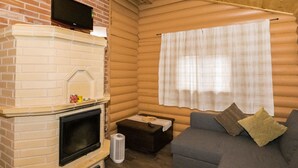 A cozy living room with a fireplace, a sofa, and a window with curtains. - Mäntymäki by Interhome (Raasepori)