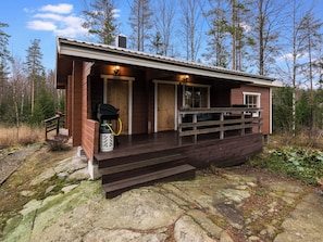 A cabin with a wooden deck, a covered porch, and a small outdoor seating area. - Mäntymäki by Interhome (Raasepori)