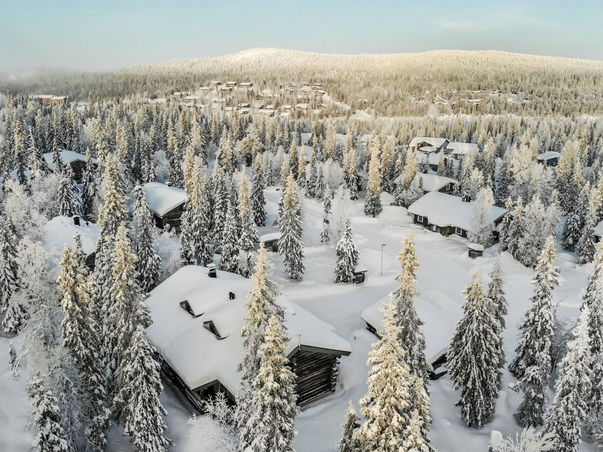 En snötäckt skog med flera stugor.