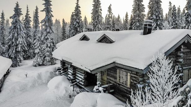 Eine Blockhütte, umgeben von schneebedeckten Bäumen.