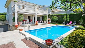 A two-story house with a swimming pool, outdoor seating, and a well-maintained garden.