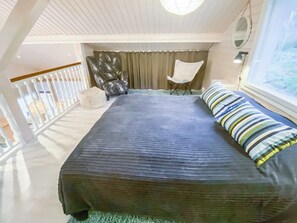 Een slaapkamer met een bed, een stoel, een raam en uitzicht op het landschap.