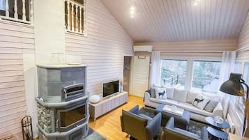 Una sala de estar acogedora con chimenea, un conjunto de sofás y una televisión.