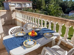 A balcony with a table set for two, white chairs, and a blue tablecloth. - Eurosol by Interhome (Miami Platja)