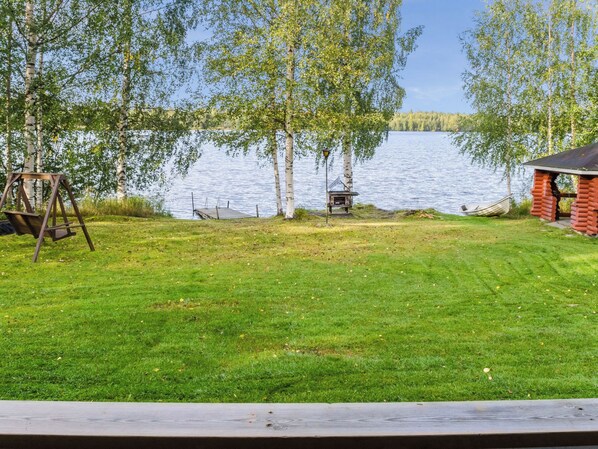 A grassy area with a swing set, a dock, and a small cabin by a lake. - Iltarauha by Interhome (Polvijärvi)