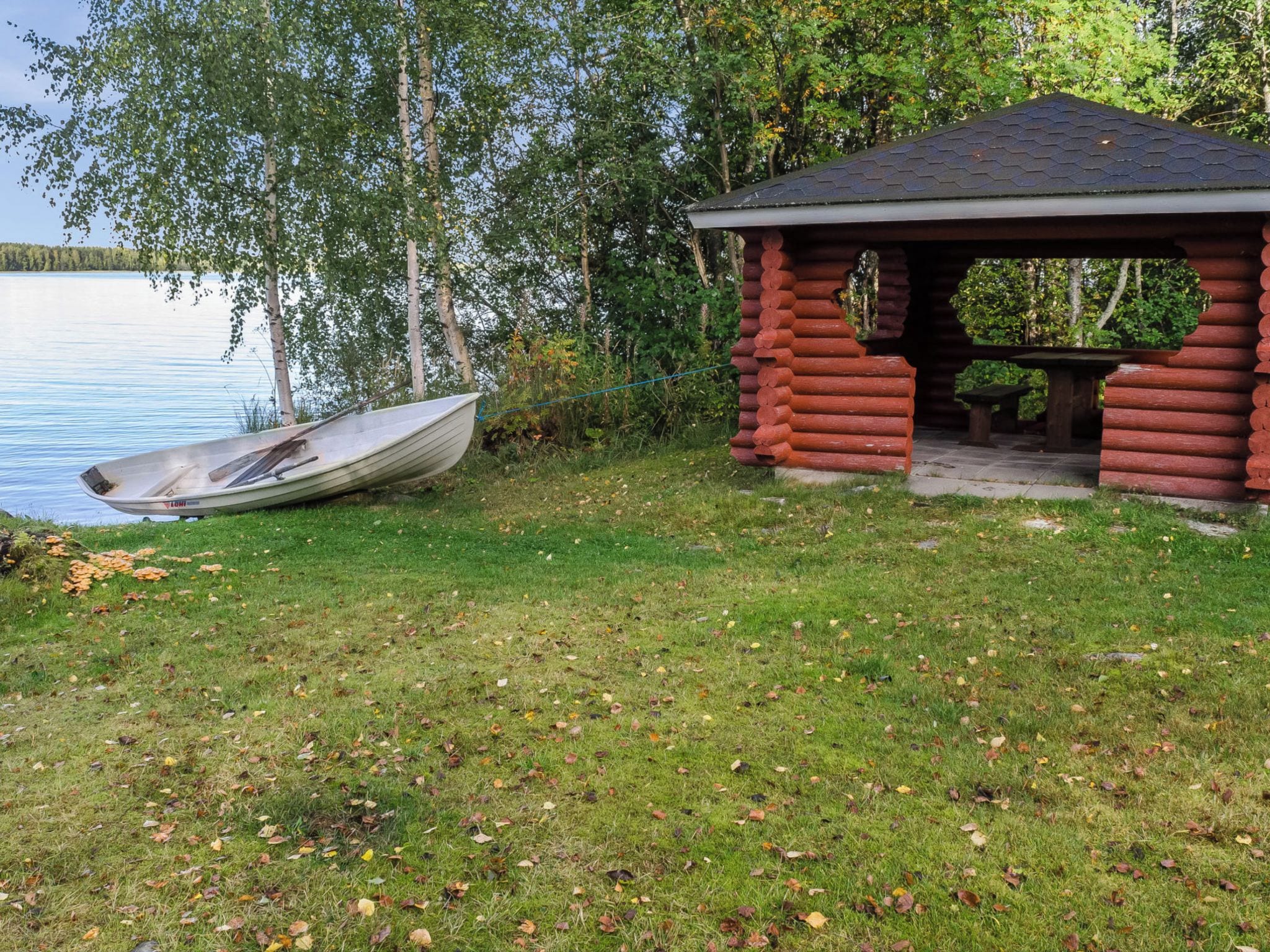 Una cabaña junto al lago con un bote amarrado cerca.