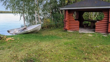 Una cabaña junto al lago con un bote amarrado cerca.