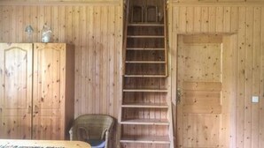 A wooden interior with a staircase, a chair, and a cabinet.