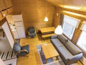 A cozy cabin interior with a sofa, chairs, a dining table, and a kitchen area.