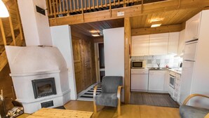 A compact kitchen with white cabinets, a microwave, and a built-in oven. There's a wooden table and a gray armchair in the living area.