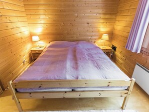 A single bed in a wooden room with two bedside lamps.