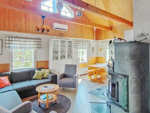 Ein gemütliches Blockhaus-Interieur mit Sofa, Sessel, Esstisch und Kaminofen.