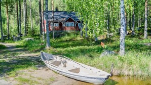 A small boat on a wooden dock by a clear water body, with a cabin in the background surrounded by a forest. - Uniranta by Interhome (Juuka)